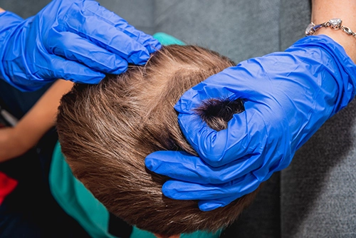 Technician examining child's scalp with professional comb