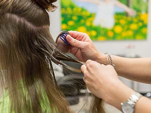 Person using a nit comb on long hair, emphasizing lice prevention and treatment for school-age children.